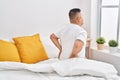 Young latin man suffering for back injury sitting on bed at bedroom Royalty Free Stock Photo