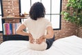 Young latin man suffering for back injury sitting on bed at bedroom Royalty Free Stock Photo