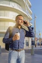 Young latin man talking on the mobile phone and holding a paper cup with coffee in his hand Royalty Free Stock Photo