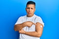 Young latin man using glucose meter button on arm depressed and worry for distress, crying angry and afraid