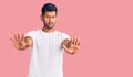 Young latin man wearing casual clothes doing stop gesture with hands palms, angry and frustration expression Royalty Free Stock Photo