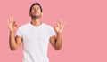 Young latin man wearing casual clothes relaxed and smiling with eyes closed doing meditation gesture with fingers Royalty Free Stock Photo