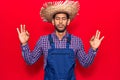 Young latin man wearing farmer hat and apron relax and smiling with eyes closed doing meditation gesture with fingers Royalty Free Stock Photo