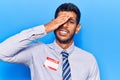 Young latin man wearing sticker with hello my name is message stressed and frustrated with hand on head, surprised and angry face