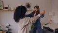 Young latin mother having fun with her daughter dancing on the sofa at home.