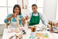 Young latin painter couple smiling happy using manikin sitting on the table at art studio Royalty Free Stock Photo