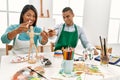 Young latin painter couple smiling happy using manikin sitting on the table at art studio Royalty Free Stock Photo