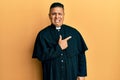 Young latin priest man standing over yellow background pointing aside worried and nervous with forefinger, concerned and surprised