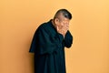 Young latin priest man standing over yellow background with sad expression covering face with hands while crying Royalty Free Stock Photo