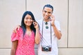 Young latin tourist couple talking on the smartphone at street of city Royalty Free Stock Photo