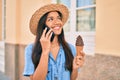 Young latin tourist girl on vacation talking on the smartphone and eating ice cream at the city Royalty Free Stock Photo