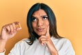 Young latin transsexual transgender woman holding pill serious face thinking about question with hand on chin, thoughtful about Royalty Free Stock Photo