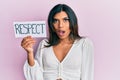 Young latin transsexual transgender woman holding respect message paper scared and amazed with open mouth for surprise, disbelief