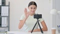 Young Latin Woman Blogging on Smartphone, Waving hand