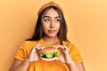 Young latin woman eating a tasty classic burger smiling looking to the side and staring away thinking Royalty Free Stock Photo