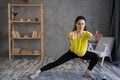 Young latin woman exercising at home, stretching legs and arms. Workout with resistance band on grey background. sport Royalty Free Stock Photo