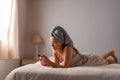 Young latin woman freshly bathed with mobile phone in the bed