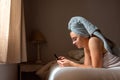 Young latin woman freshly bathed with mobile phone in the bed