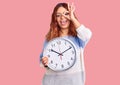 Young latin woman holding big clock smiling happy doing ok sign with hand on eye looking through fingers Royalty Free Stock Photo