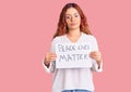 Young latin woman holding black lives matter banner thinking attitude and sober expression looking self confident Royalty Free Stock Photo