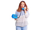 Young latin woman holding vintage telephone scared and amazed with open mouth for surprise, disbelief face Royalty Free Stock Photo