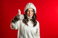 Young latin woman in knitted hat, mittens, sweater smiling and showing thumbs up Royalty Free Stock Photo