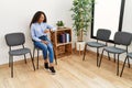 Young latin woman looking watch sitting on chair at waiting room Royalty Free Stock Photo