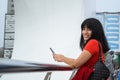 young latin woman outdoors on a cloudy day, texting and looking at the camera smiling