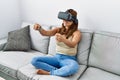Young latin woman playing video game using virtual reality glasses at home Royalty Free Stock Photo