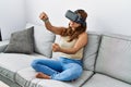 Young latin woman playing video game using virtual reality glasses at home Royalty Free Stock Photo