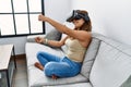 Young latin woman playing video game using virtual reality glasses at home Royalty Free Stock Photo