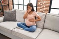 Young latin woman pregnant with puke expession at home