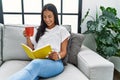 Young latin woman reading book drinking coffee at home Royalty Free Stock Photo