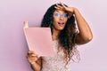 Young latin woman reading a book with glasses stressed and frustrated with hand on head, surprised and angry face Royalty Free Stock Photo