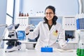 Young latin woman scientist writing on notebook holding pills at laboratory Royalty Free Stock Photo