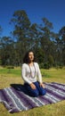 Young latin woman sitting meditating in the park