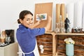 Young latin woman smiling confident hanging draw paper on corkboard at art studio Royalty Free Stock Photo