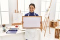 Young latin woman smiling confident holding whiteboard at art studio Royalty Free Stock Photo