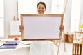 Young latin woman smiling confident holding whiteboard at art studio Royalty Free Stock Photo