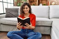 Young latin woman smiling confident reading bible at home