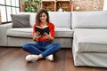 Young latin woman smiling confident reading bible at home