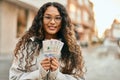 Young latin woman smiling happy holding colombia pesos banknotes at the city