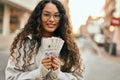 Young latin woman smiling happy holding colombia pesos banknotes at the city