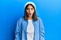 Young latin woman wearing cute wool cap afraid and shocked with surprise and amazed expression, fear and excited face Royalty Free Stock Photo