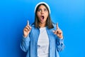 Young latin woman wearing cute wool cap amazed and surprised looking up and pointing with fingers and raised arms Royalty Free Stock Photo