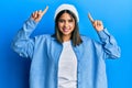 Young latin woman wearing cute wool cap smiling amazed and surprised and pointing up with fingers and raised arms Royalty Free Stock Photo