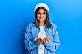 Young latin woman wearing cute wool cap smiling with hands palms together receiving or giving gesture Royalty Free Stock Photo