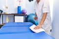 Young latin woman wearing physiotherapist uniform cleaning massage table at physiotherapy clinic Royalty Free Stock Photo