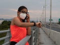 Latina girl checks her watch while talking on the phone on a bridge after a run Royalty Free Stock Photo