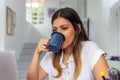 Young latina woman drinking coffee working on a laptop and sitting at homeoffice Royalty Free Stock Photo